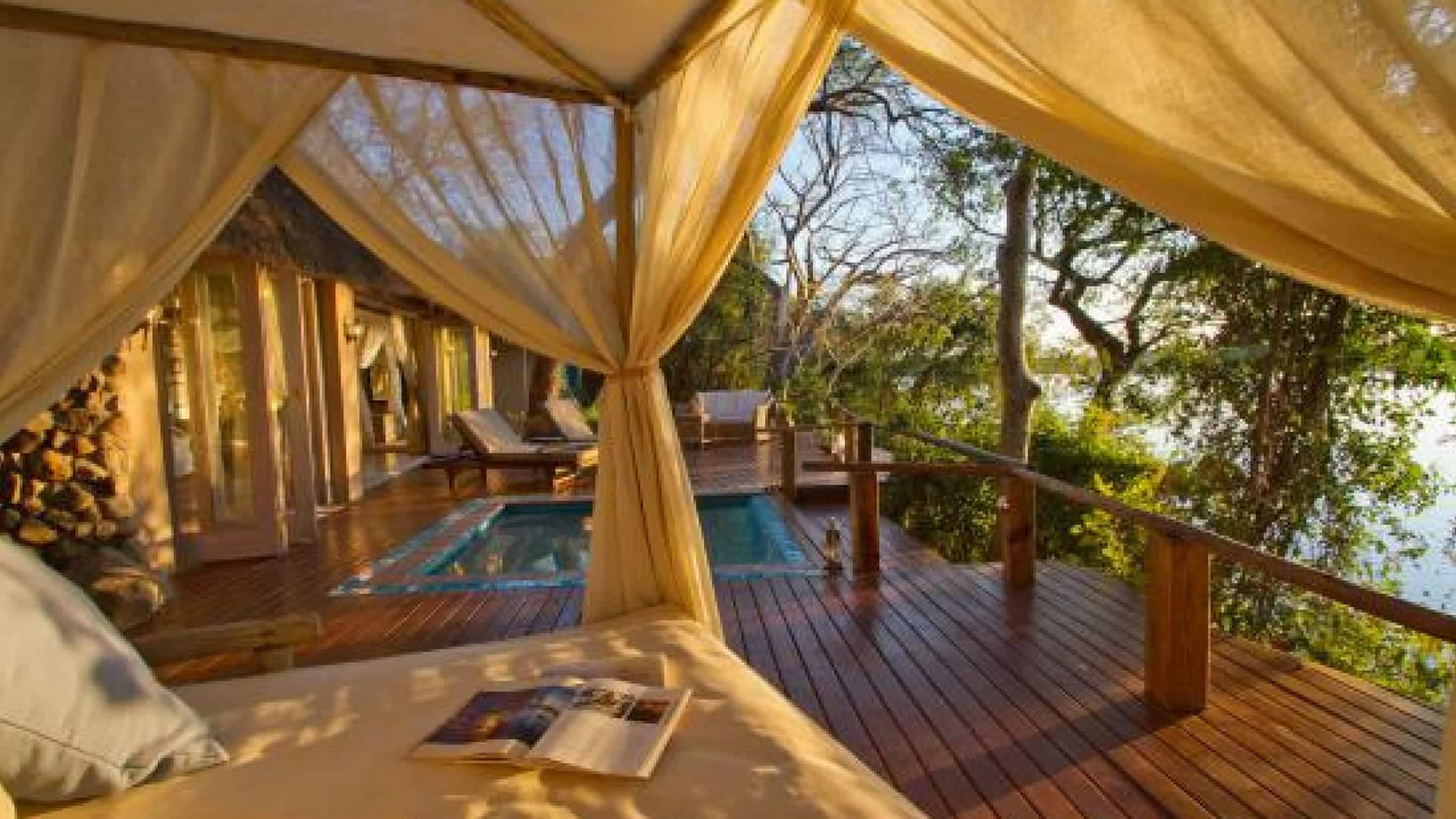 A plunge pool and netted daybed on a deck next to the Zambezi at Tongabezi