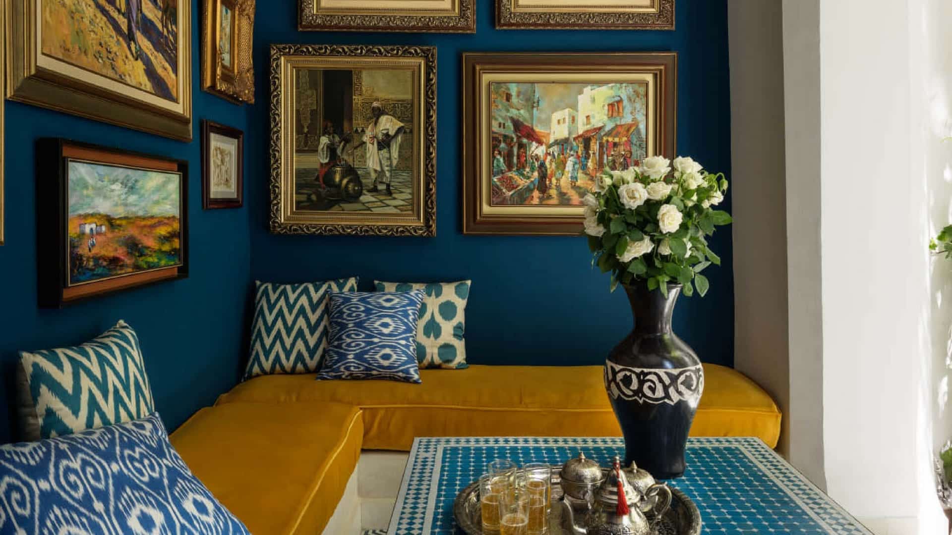 A blue walled sitting nook hung with fine paintings at Riad les Yeux Bleu