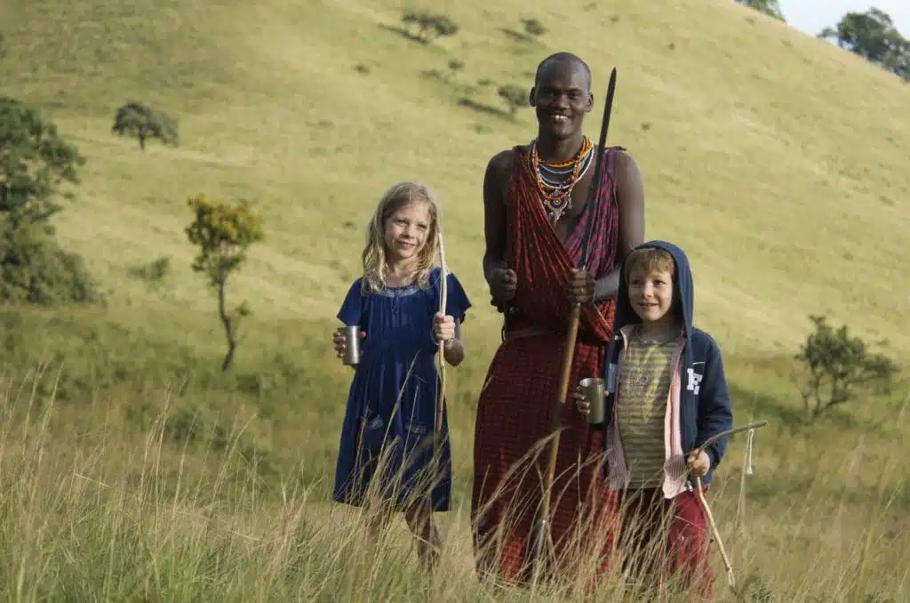 Two children on walking safari with masai warrior
