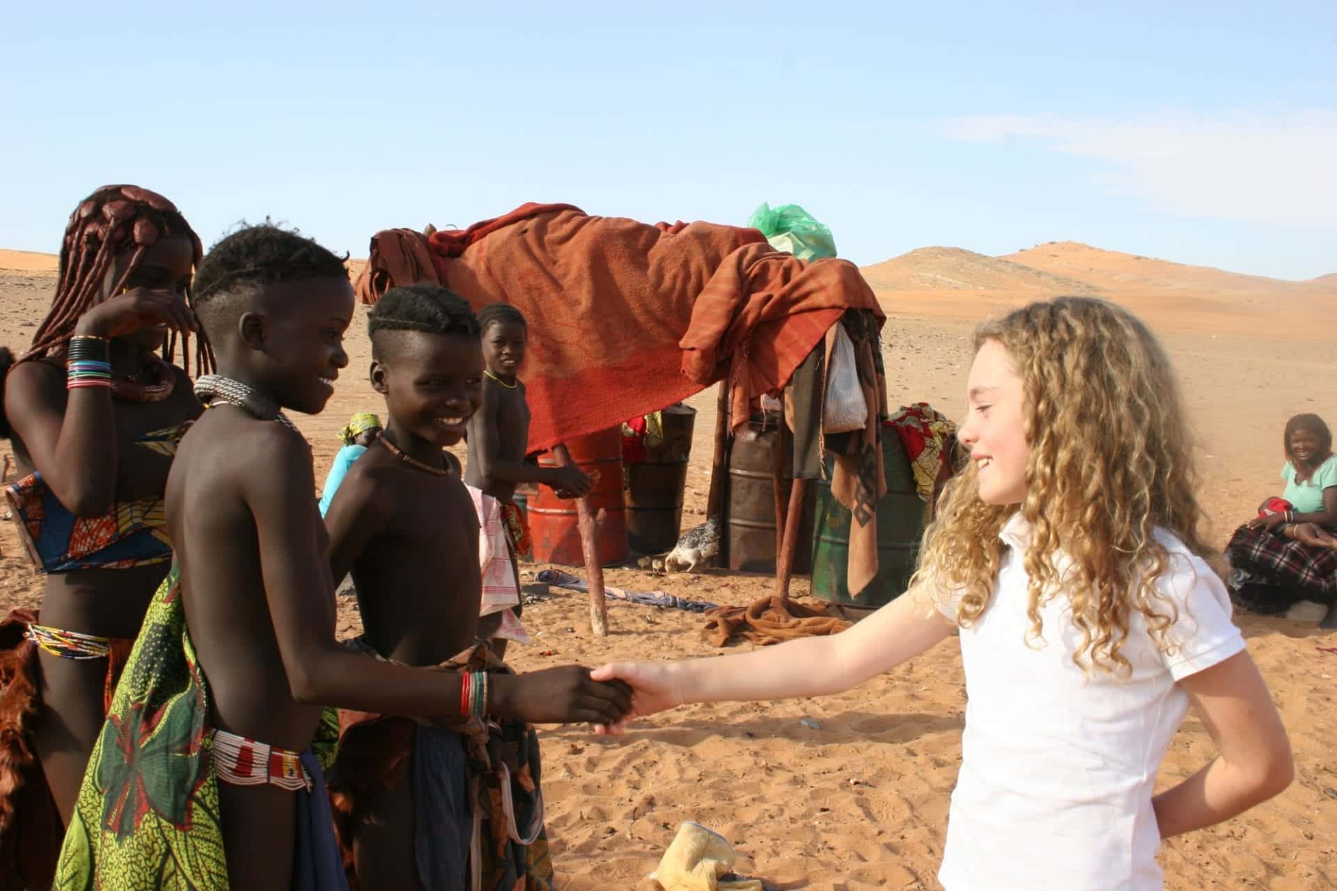 Young girl shaking hands with Himba people